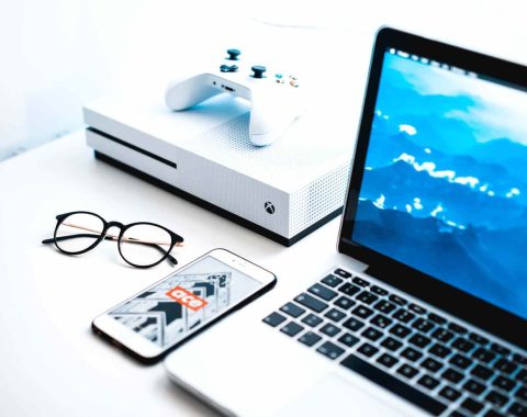 portátil, consola de juegos y teléfono encima de una mesa